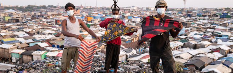 Brandneue Textilien werden von Textilunternehmen weggeworfen und landen auf überquellenden Müllhalden in Jamestown, Ghana, wo sie von Aktivist*innen ins Bild gehalten werden.